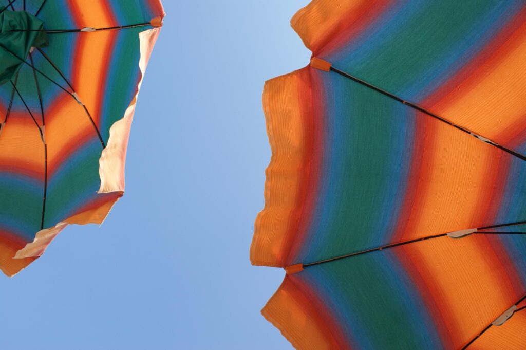 Parasol In The Sun Blue Skies. Image used under a Collective Commons License from https://pixabay.com/photos/heat-sun-bathing-summer-holiday-831822/
